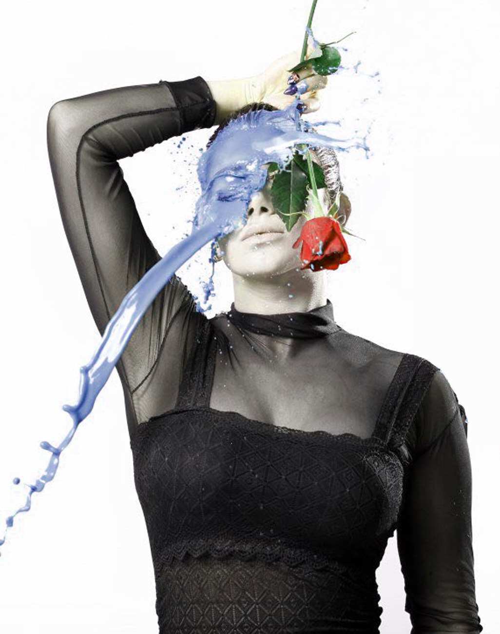 A woman holding a red rose as blue paint splashes across her face